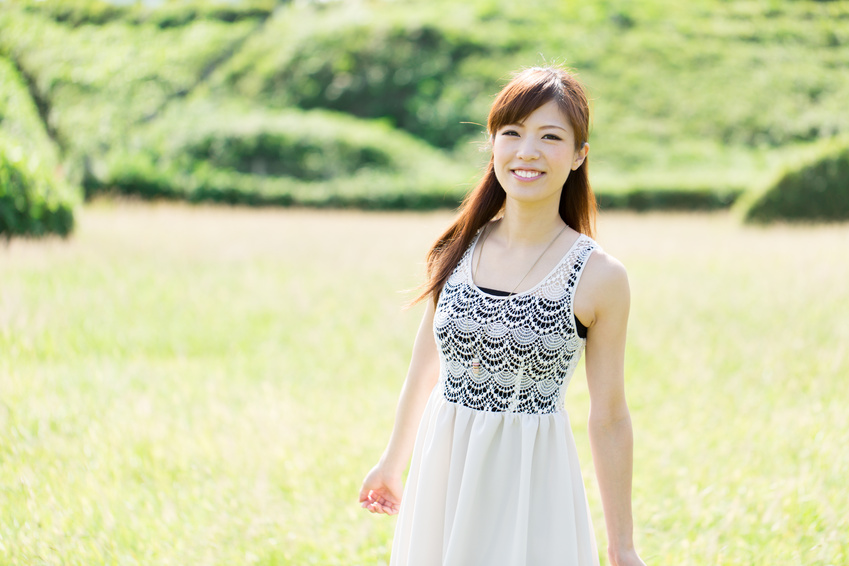 Beautiful young woman on green field. Portrait of asian.
